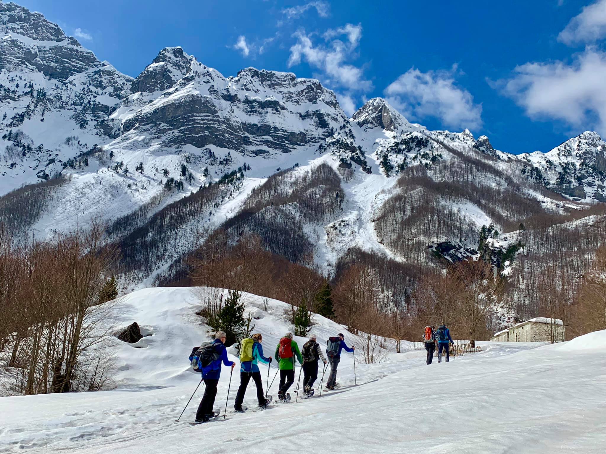 Schneeschuhgruppe unter verschneiten Felswänden