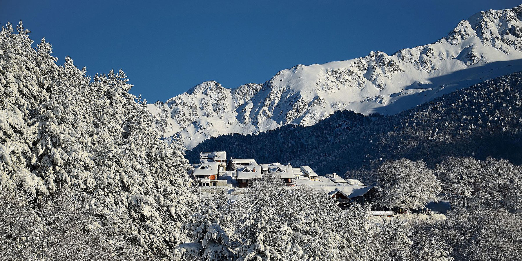 Verschneite Chalets vor dem Gebirge